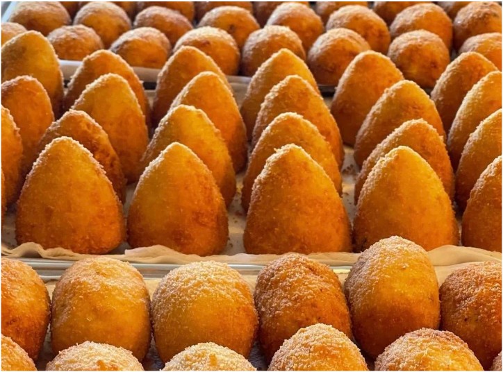 Rows of perfectly golden browned arancine rice balls in varying shapes and sizes.