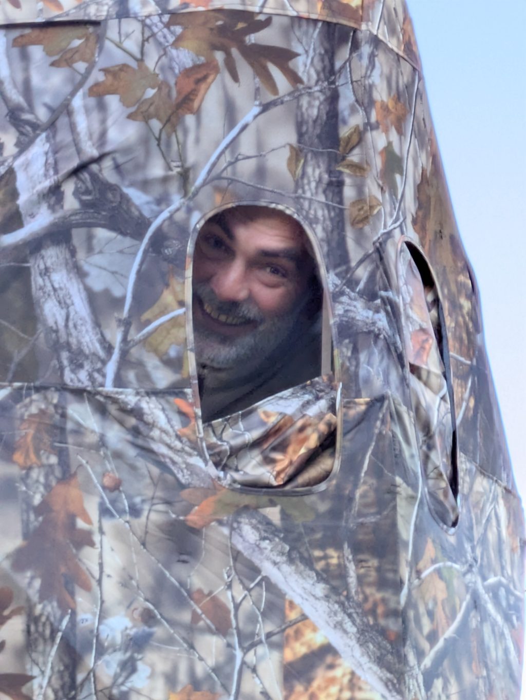 Man peeking from camouflage structure.